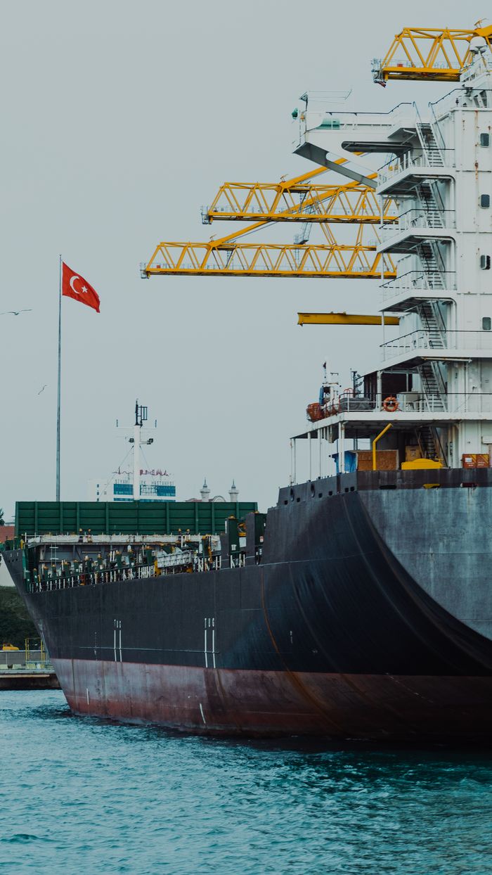 contact-img A cargo ship docked at a Turkish port, showcasing maritime industry and trade.
